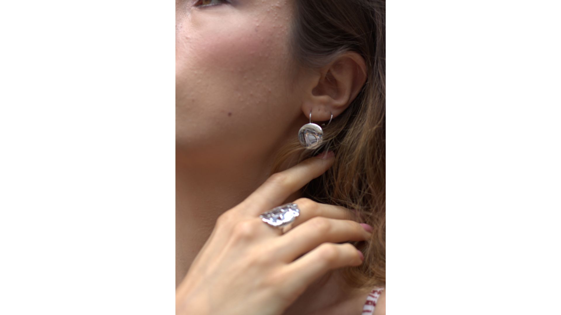 Close-up of a person wearing a ring and earrings

Description automatically generated