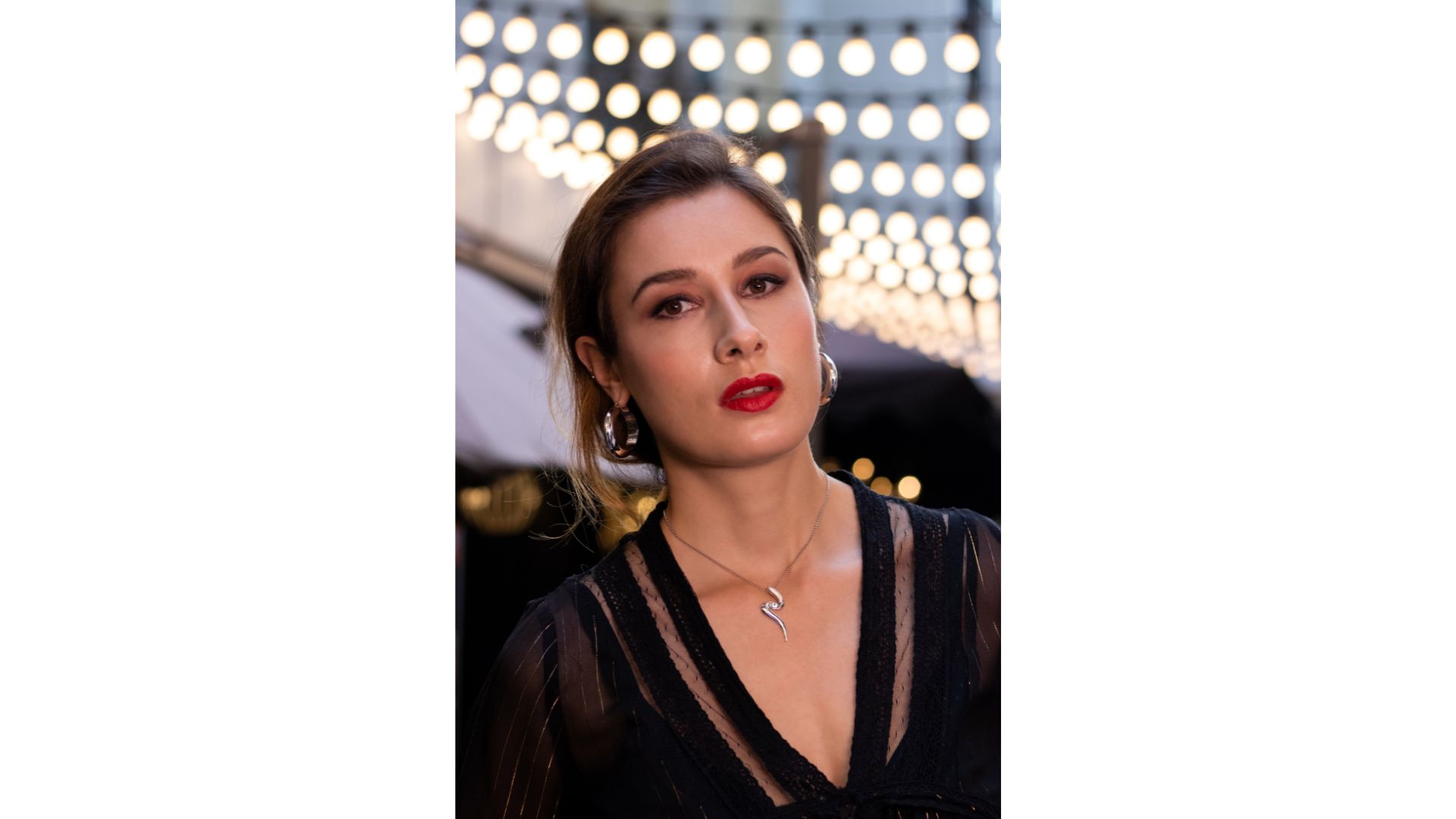 A person with red lipstick and earrings
Description automatically generated