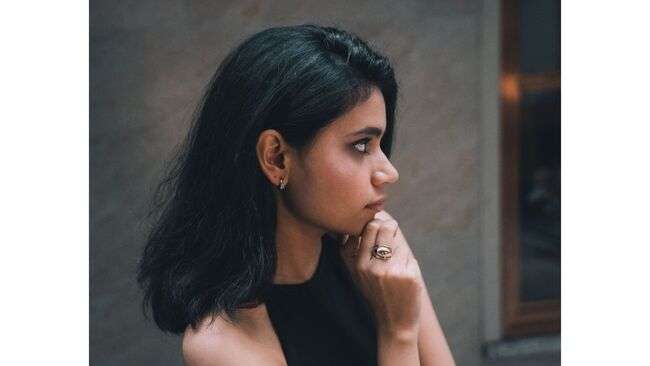 A person with her hand on her chin

Description automatically generated