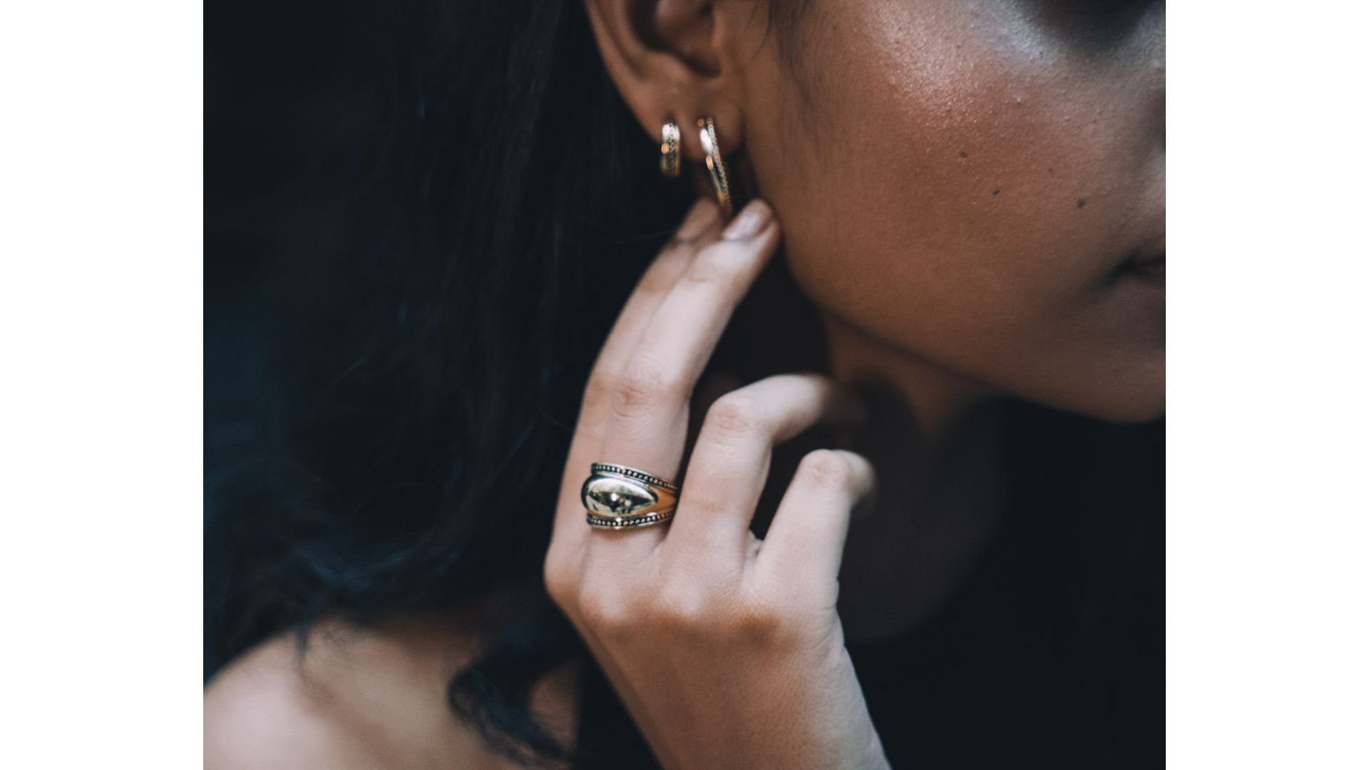 A close-up of a person's hand touching her ear
Description automatically generated