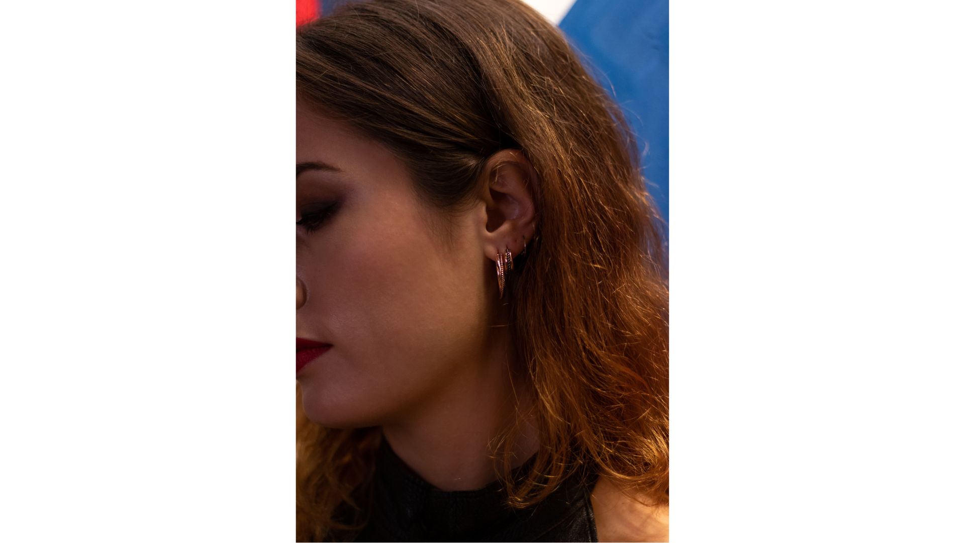 A person with red hair and earrings
Description automatically generated