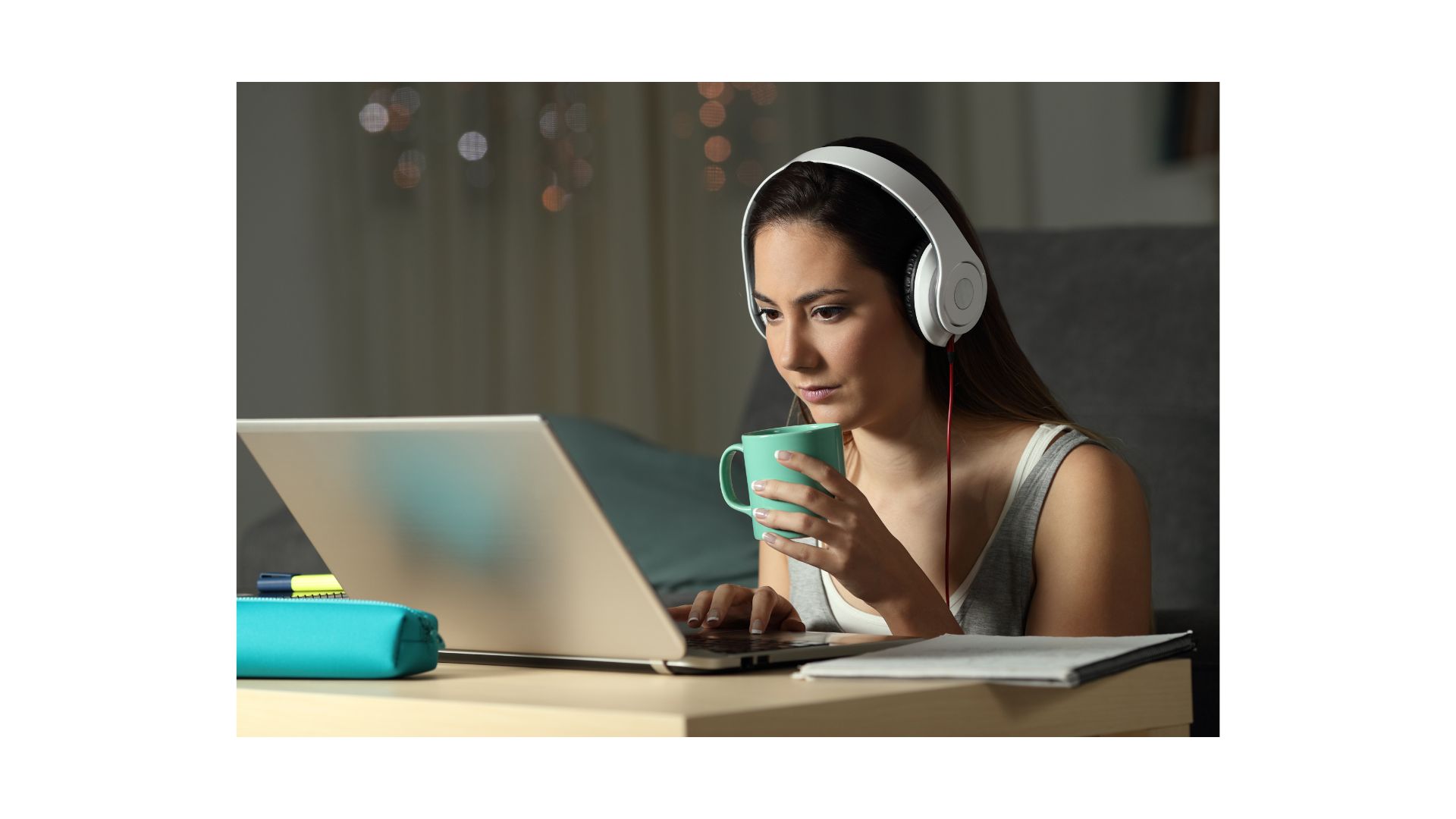 A person wearing headphones and drinking coffee while using a computer
AI-generated content may be incorrect.