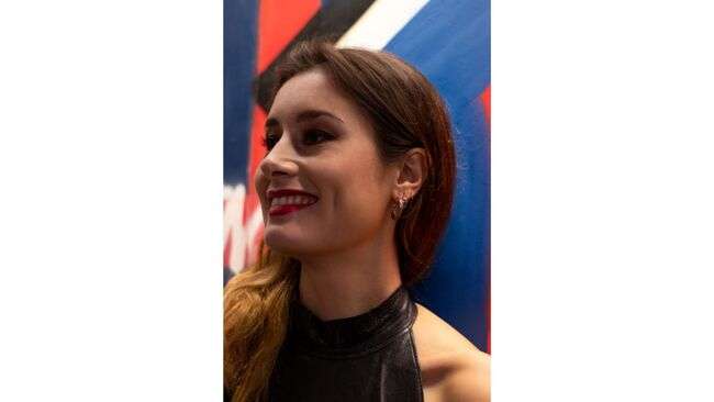 A person smiling in front of a blue and red background

Description automatically generated