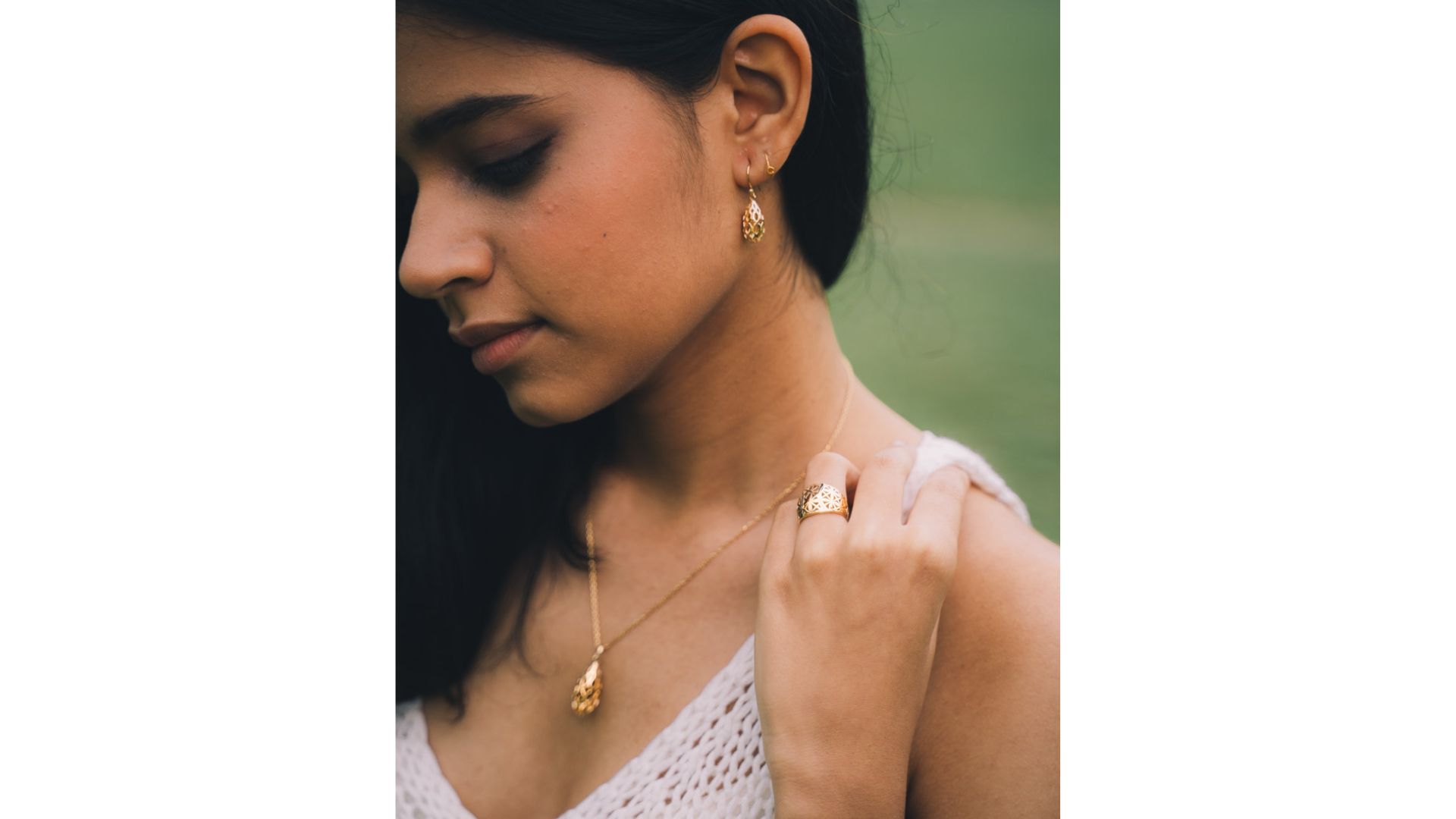 A person wearing a white top and gold necklace

Description automatically generated