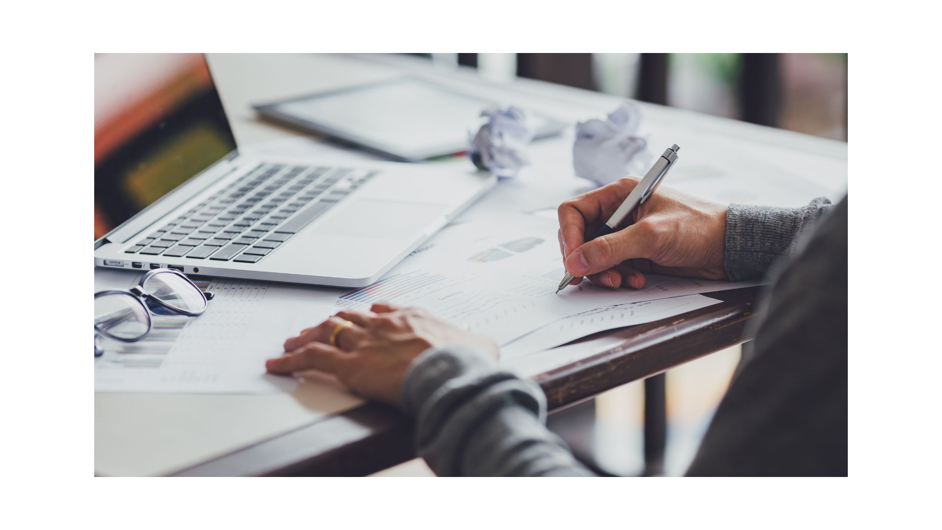 A person writing on papers
Description automatically generated