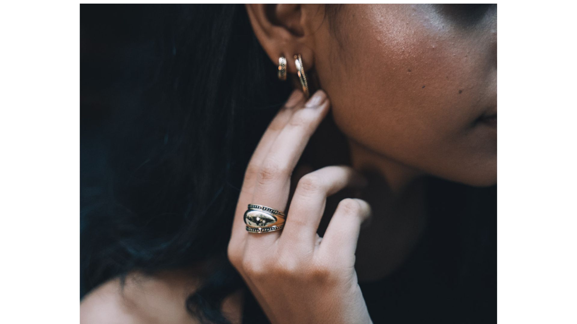 A close-up of a person's hand touching her ear
Description automatically generated