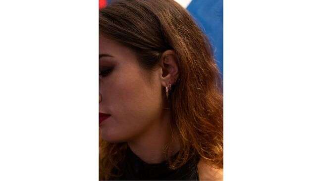 A person with red hair and earrings

Description automatically generated