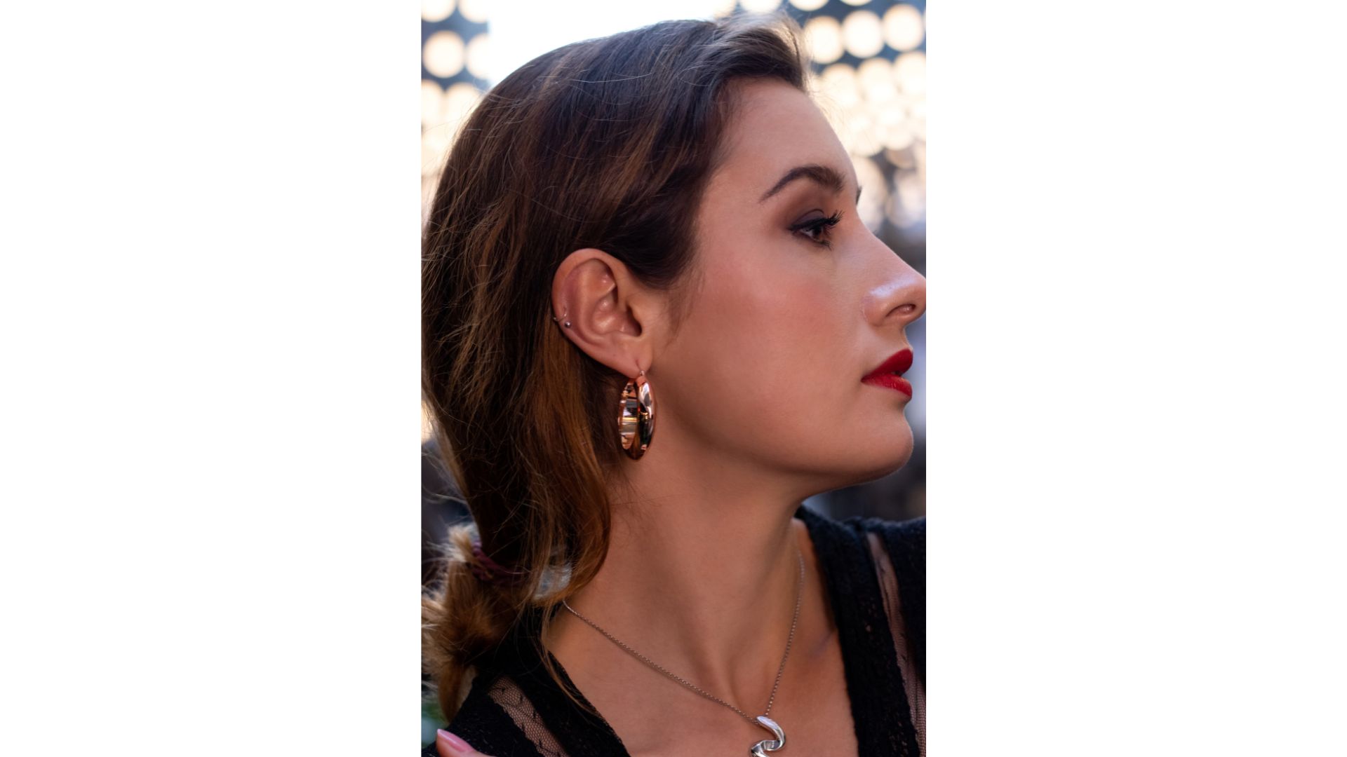A person with red lipstick and earrings
Description automatically generated