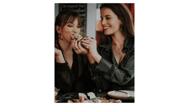 A couple of women eating food

Description automatically generated