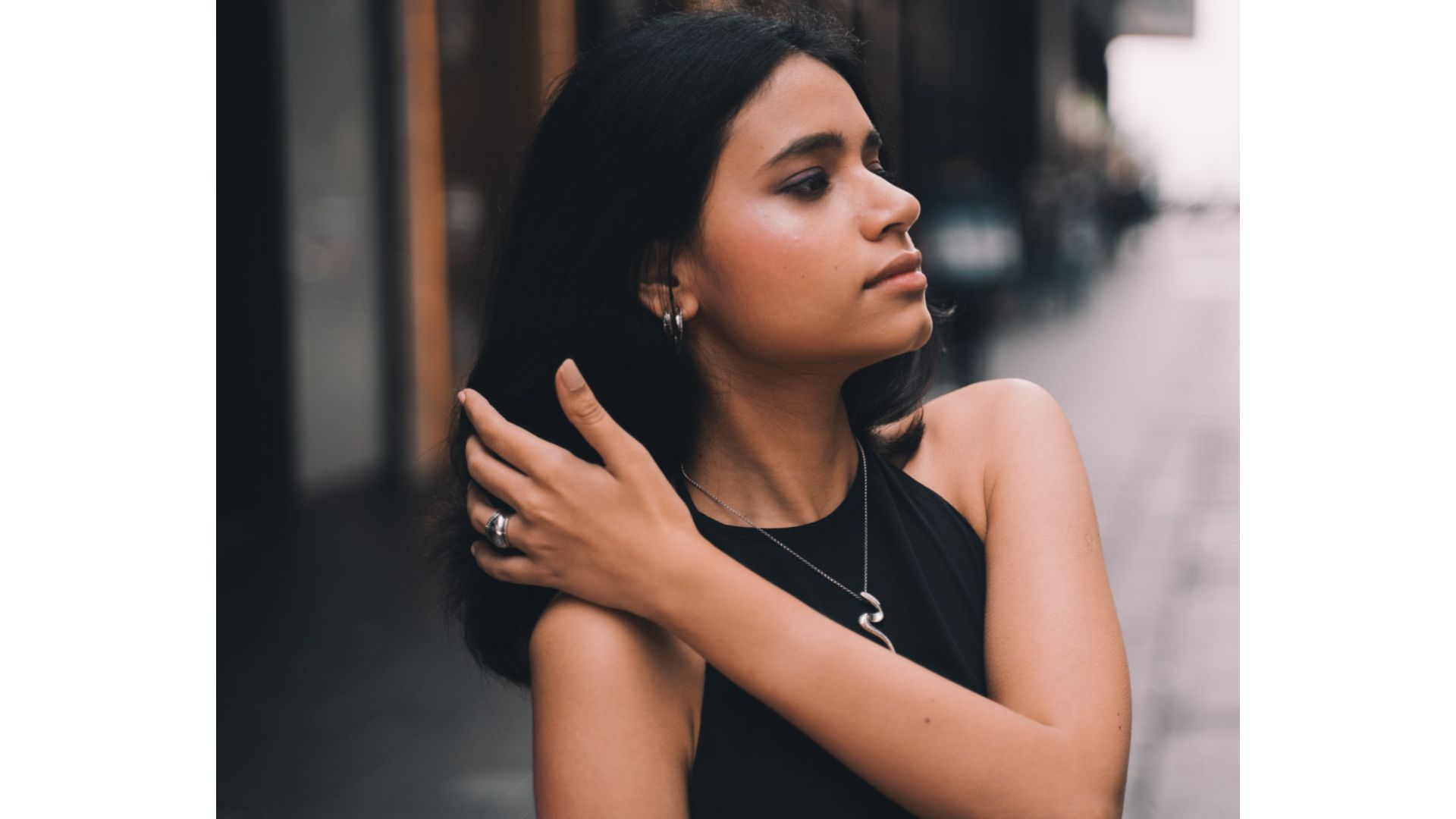A person with her hand on her shoulder
Description automatically generated